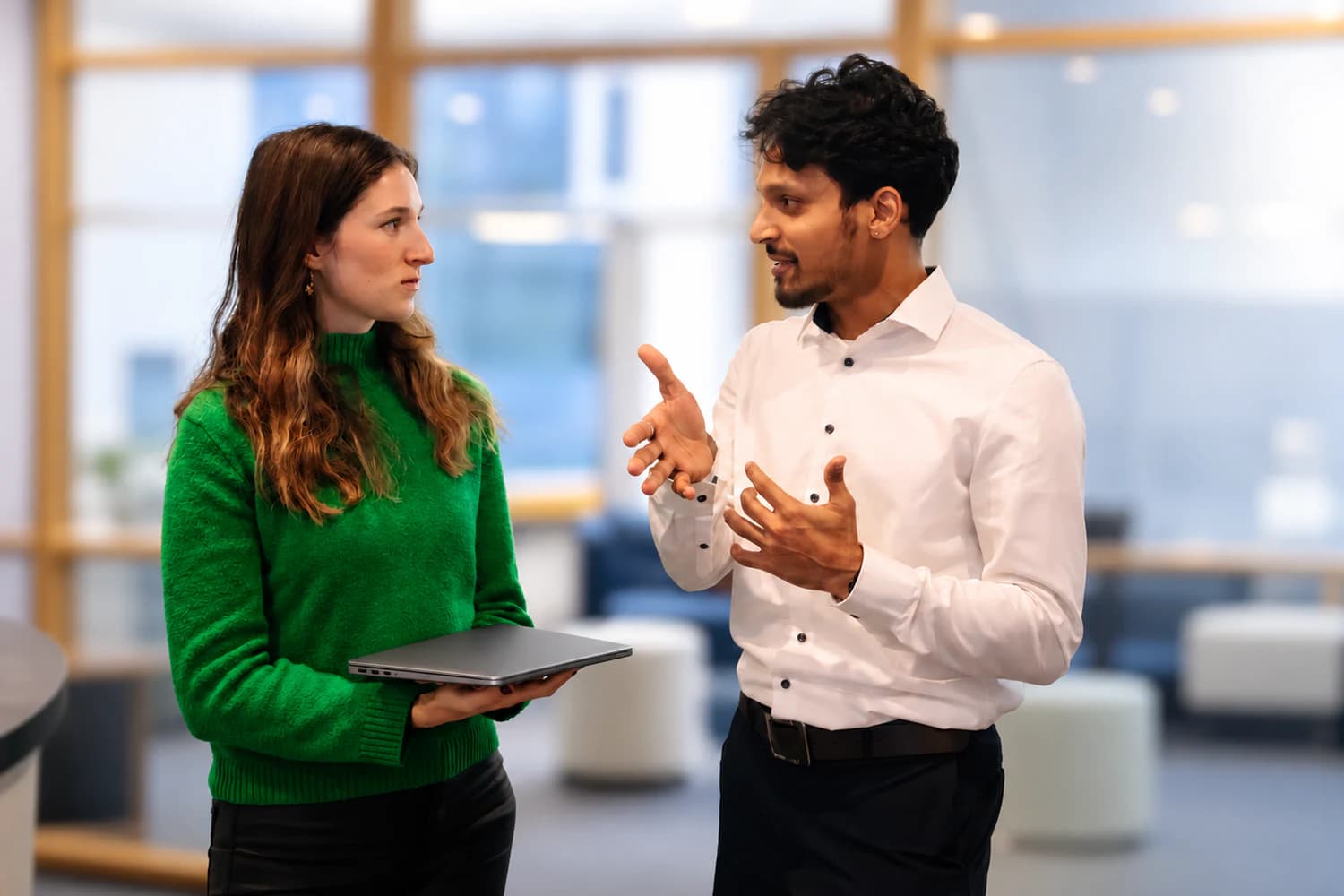 Two FrontWell colleagues discussing an idea while holding a laptop.